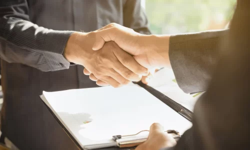 handshake over a desk with signed insurance papers